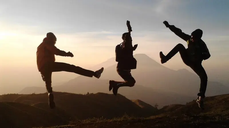 Gruppe springt vor Abendhimmel in den Bergen